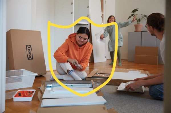 Jeune femme assise par terre, en train de monter un produit IKEA. Un logo représentant une forme de blason apparaît sur l'image en jaune