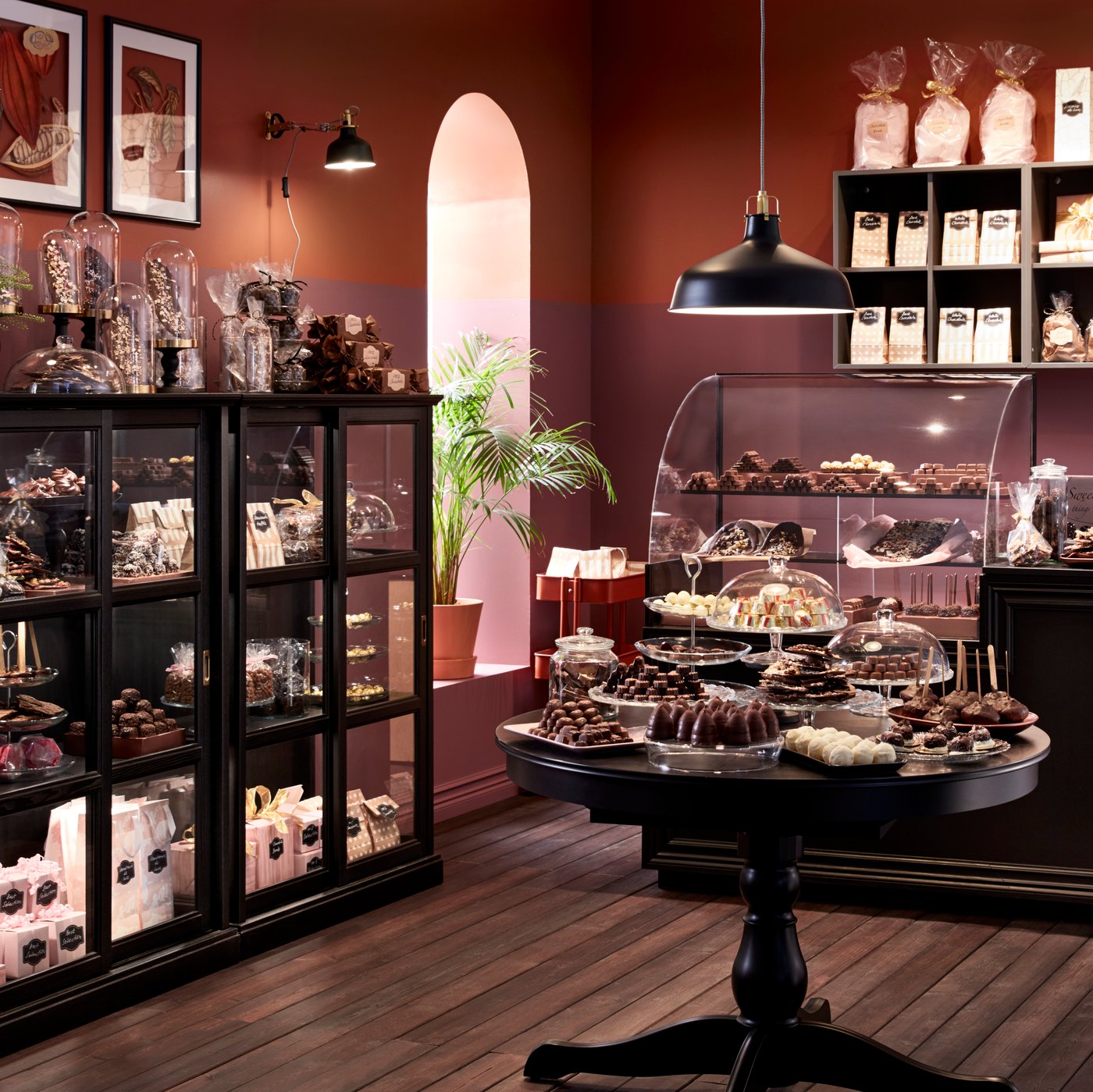 Una sala con una gran vitrina IKEA y en el costado se asoma una mesa de comedor Sobre la mesa una lámpara de techo RANARP negra.