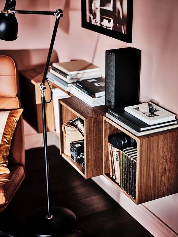 A HAVBERG armchair and footstool next to walnut veneer STOCKHOLM nest of tables, set of 2 below two EKET cabinets.