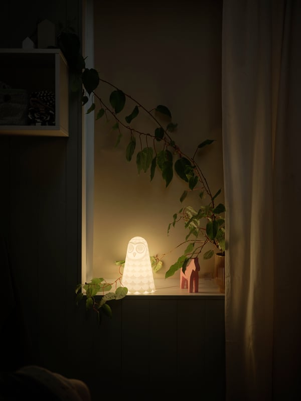A FÖNSTERBLAD block out blind closed in front of a window with a white/owl SOLBO LED table lamp on the window sill.