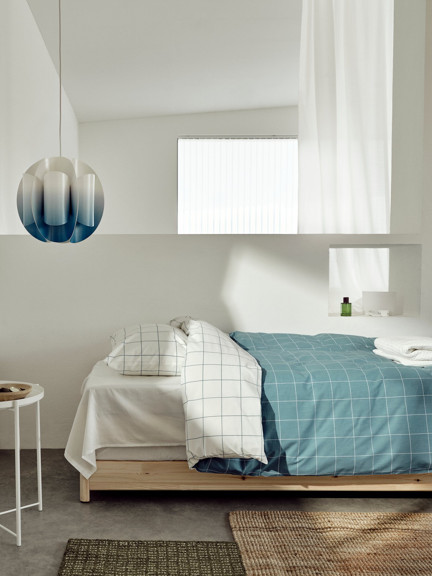 A bed styled with the VITKLÖVER quilt cover set is paired with the TRUBBNATE pendant lampshade in blue and white.