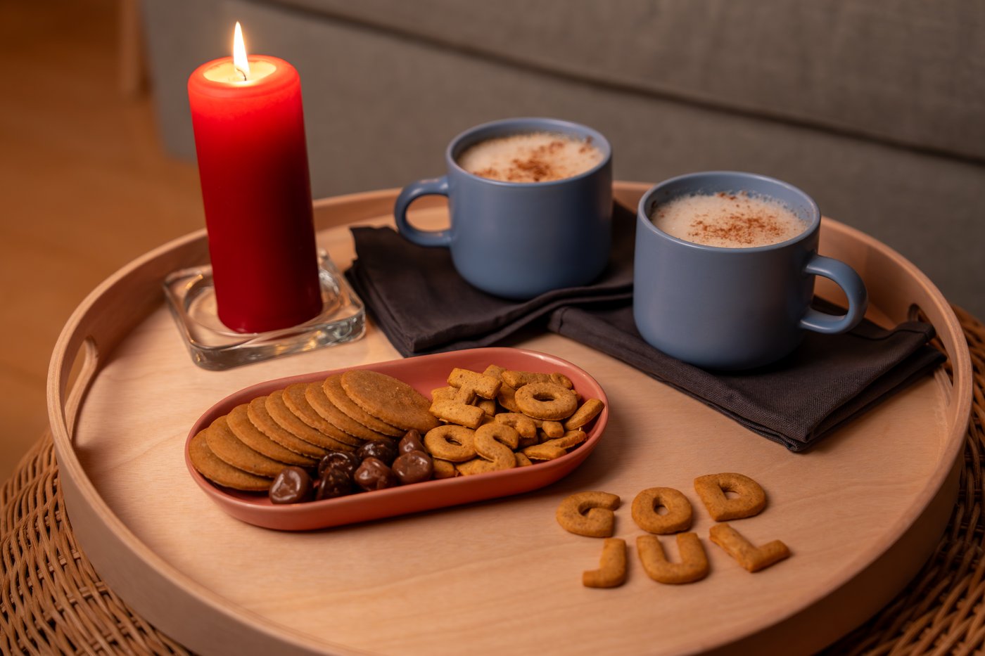 Zwei Tassen schwedischer Kakao mit einem Keksteller und einer roten Kerze auf einem Tisch präsentiert.
