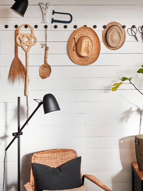 Decorative items and hats hang on a wall-mounted white rack with black knobs.