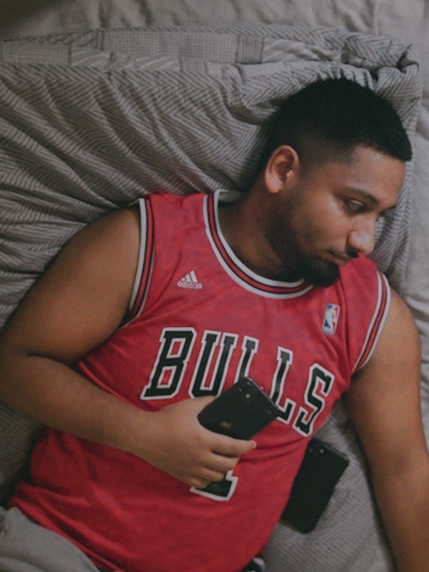 Man lying on a comfy bed, holding his phone.