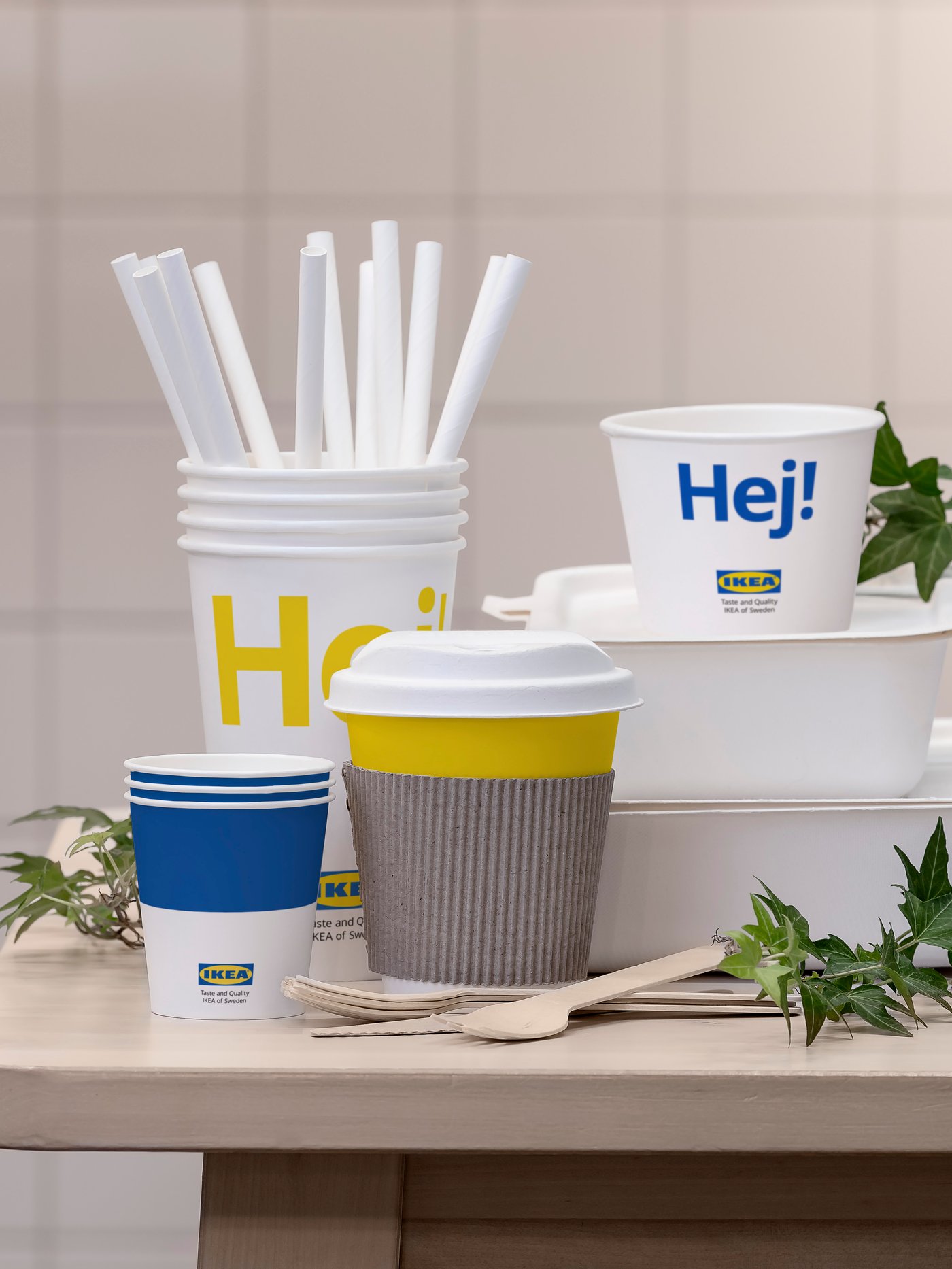 A collection of take-away food packaging including cups, straws and boxes, some with the IKEA logo and the word “Hej”.