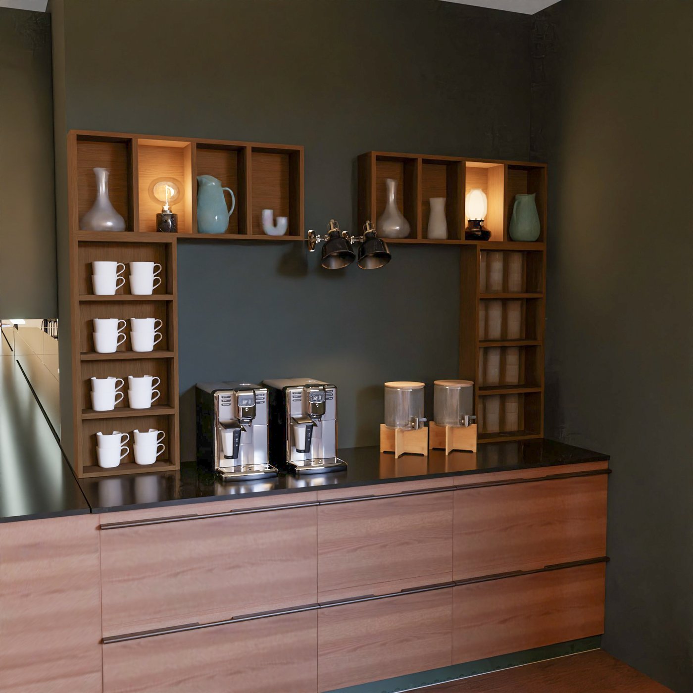 Kaffeebar mit teils offener, teils geschlossener Aufbewahrung. Im offenen Bereich Kaffeeautomaten, Wasserspender, Kaffeetassen und dekorative Accessoires.