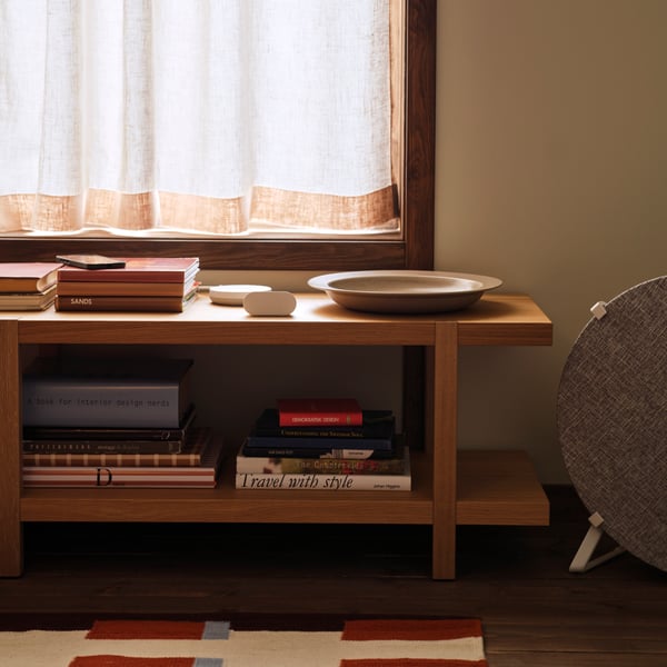 An ALPSTUGA air quality sensor sits on top of a STOCKHOLM 2025 shelving unit/bench standing next to a STARKVIND air purifier.