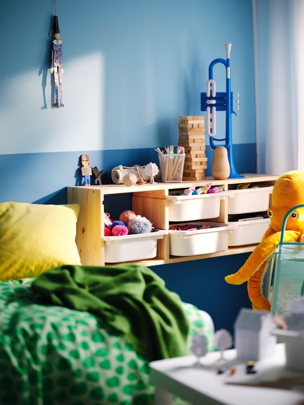 Wall-mounted TROFAST storage unit with plastic boxes full of toys, plus a lot of toys and stuff on top of it as well.