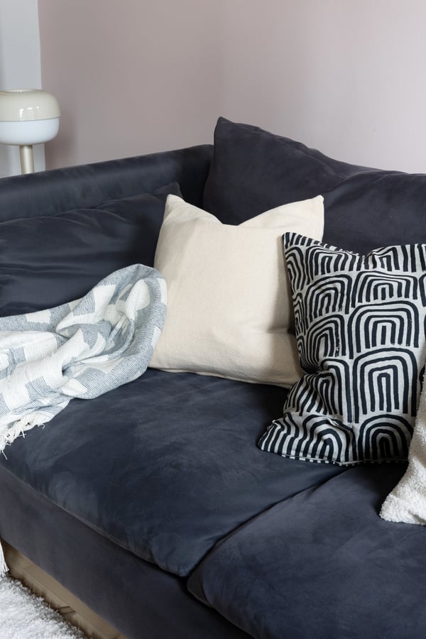En blå sofa dandert med myke puter og pledd.