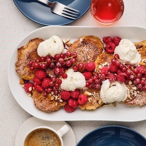 Pain perdu dans une assiette blanche. Framboises, groseilles et fraise ainsi que de la  glace vanille sur le dessus