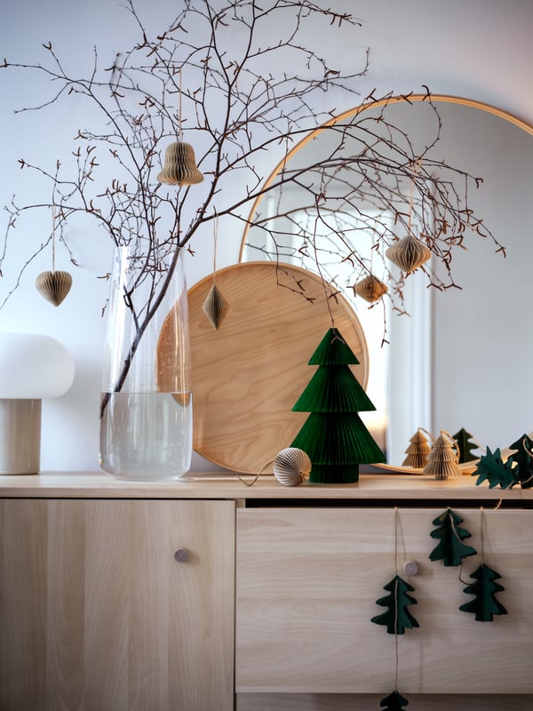Des branches et des brindilles sont disposées dans le vase BERÄKNA. Tout est paré et décoré pour Noël sur le buffet ERSNÄS.