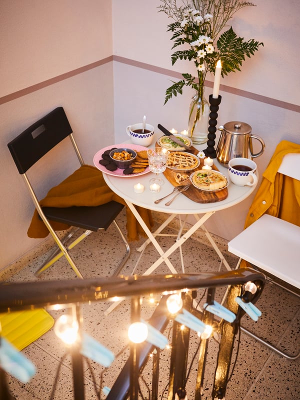 Un comedor pequeño al costado de una escalera con mesas y sillas plegables.