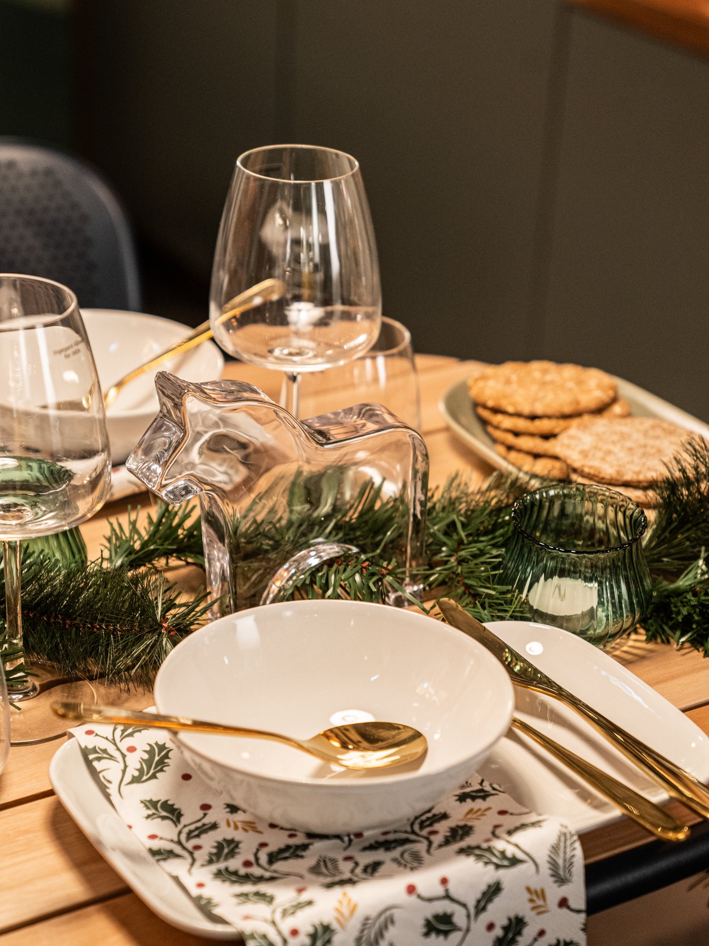 Man sieht einen festlich gedeckten Tisch mit GODMIDDAG Geschirr, TILLAG Besteck und DYRGRIP Weingläser. In der Mitte befindet sich eine grüne Girlande.
