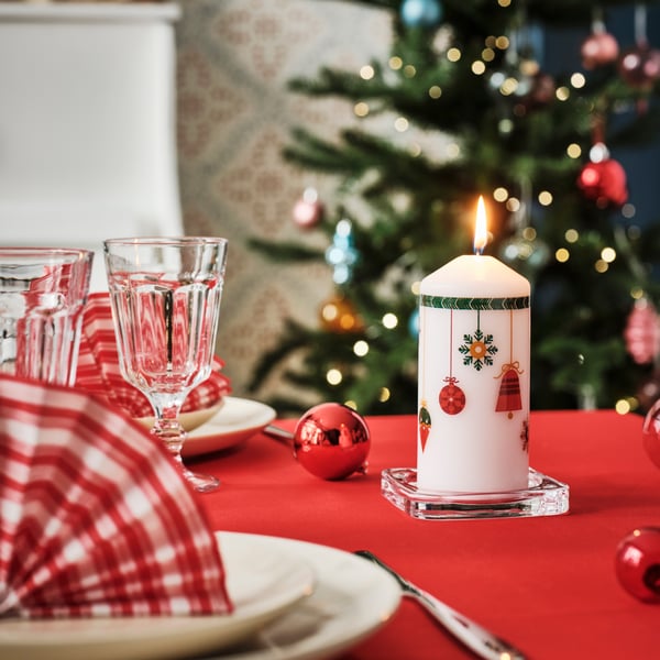 Tavolo da pranzo con tovaglia rossa e albero di Natale sullo sfondo.