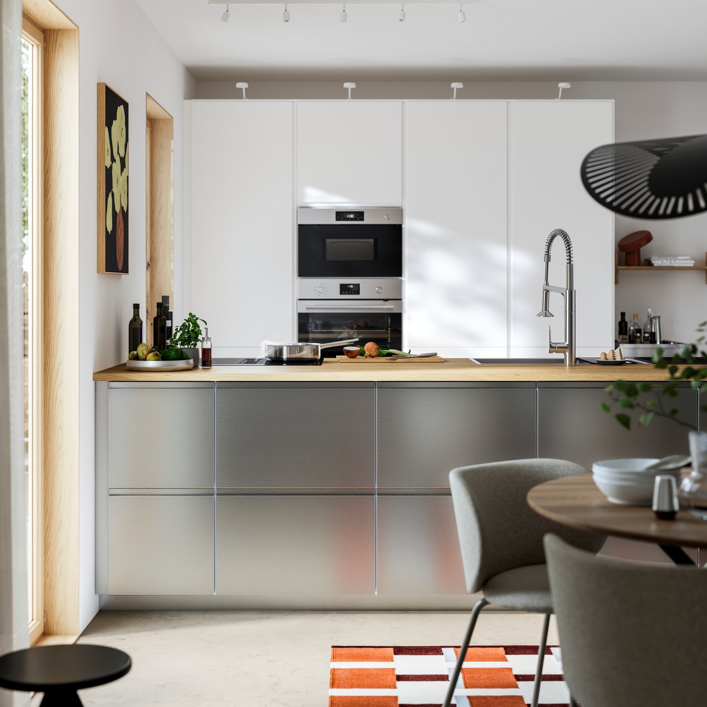 A modern minimalist kitchen where the kitchen island is fitted with VOXTORP stainless steel effect drawer fronts.