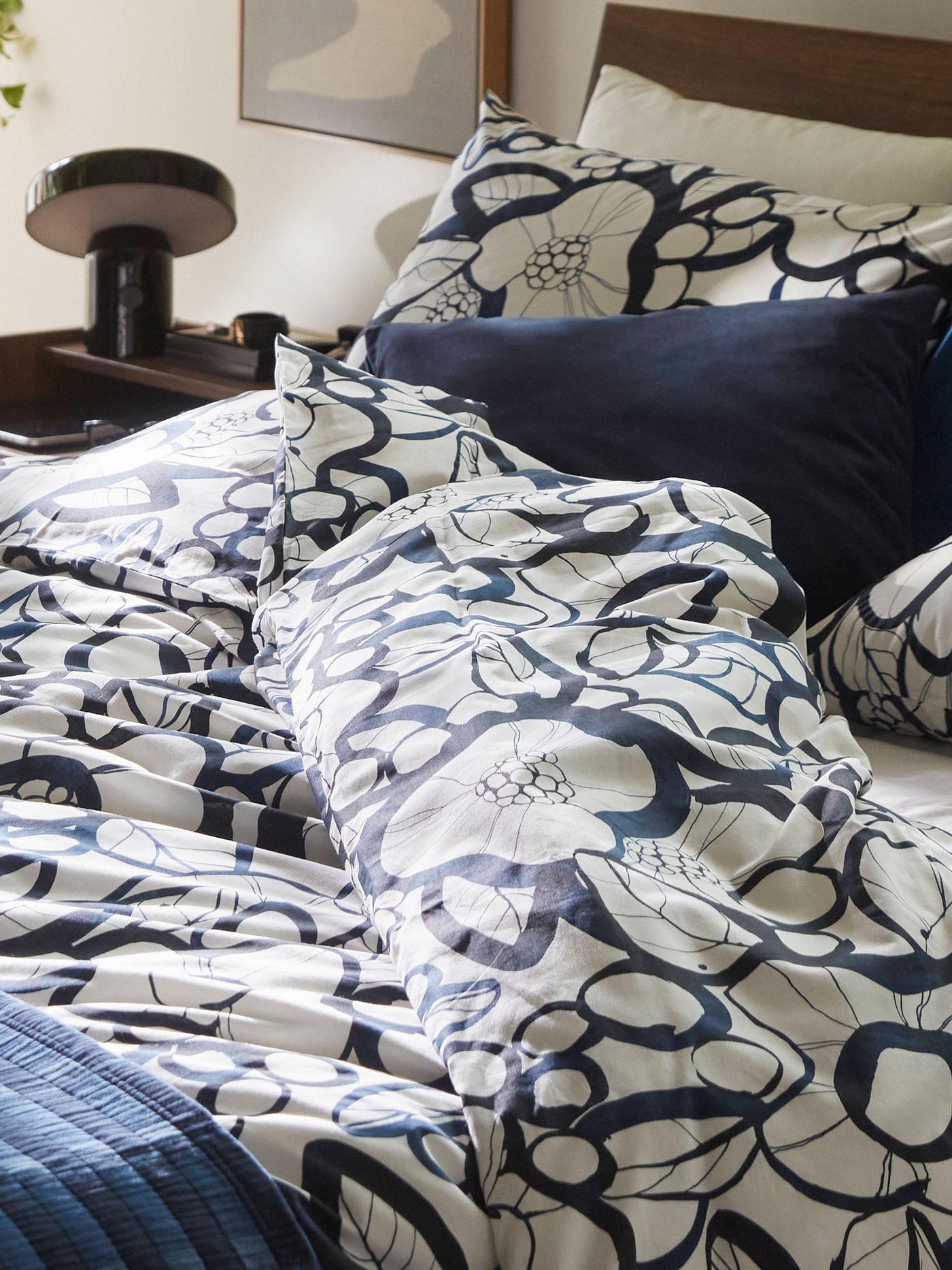 En bädd med mönstrade täcken och kuddar i blå och vita toner.