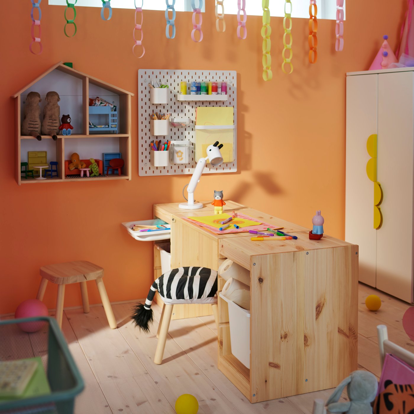 Two light, white-stained pine TROFAST frames with a tabletop make a desk in a children’s room, with a FLISAT stool in front.