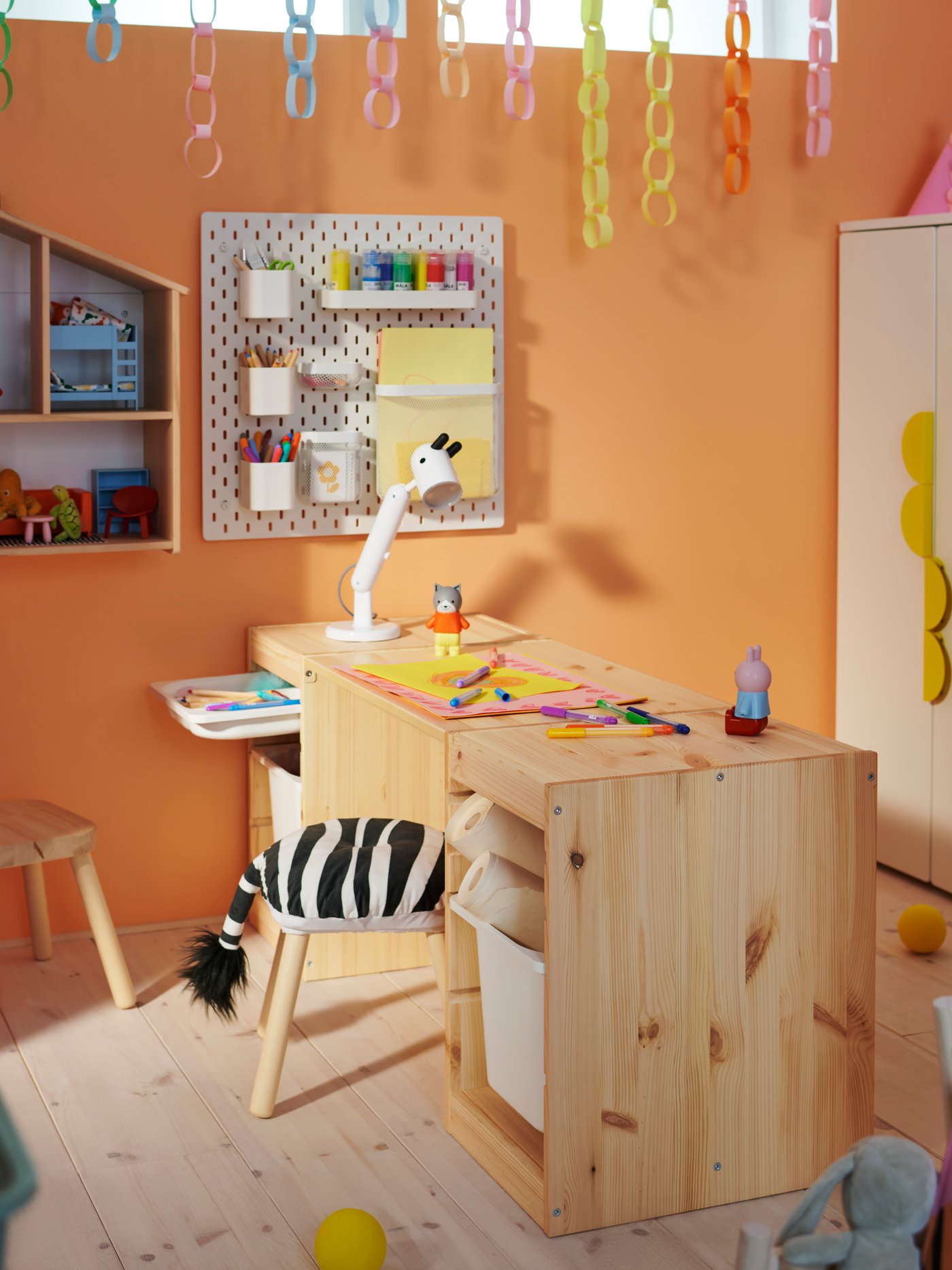 Two light white stained pine TROFAST frames with a tabletop make a desk in a children’s room with a FLISAT stool in front.