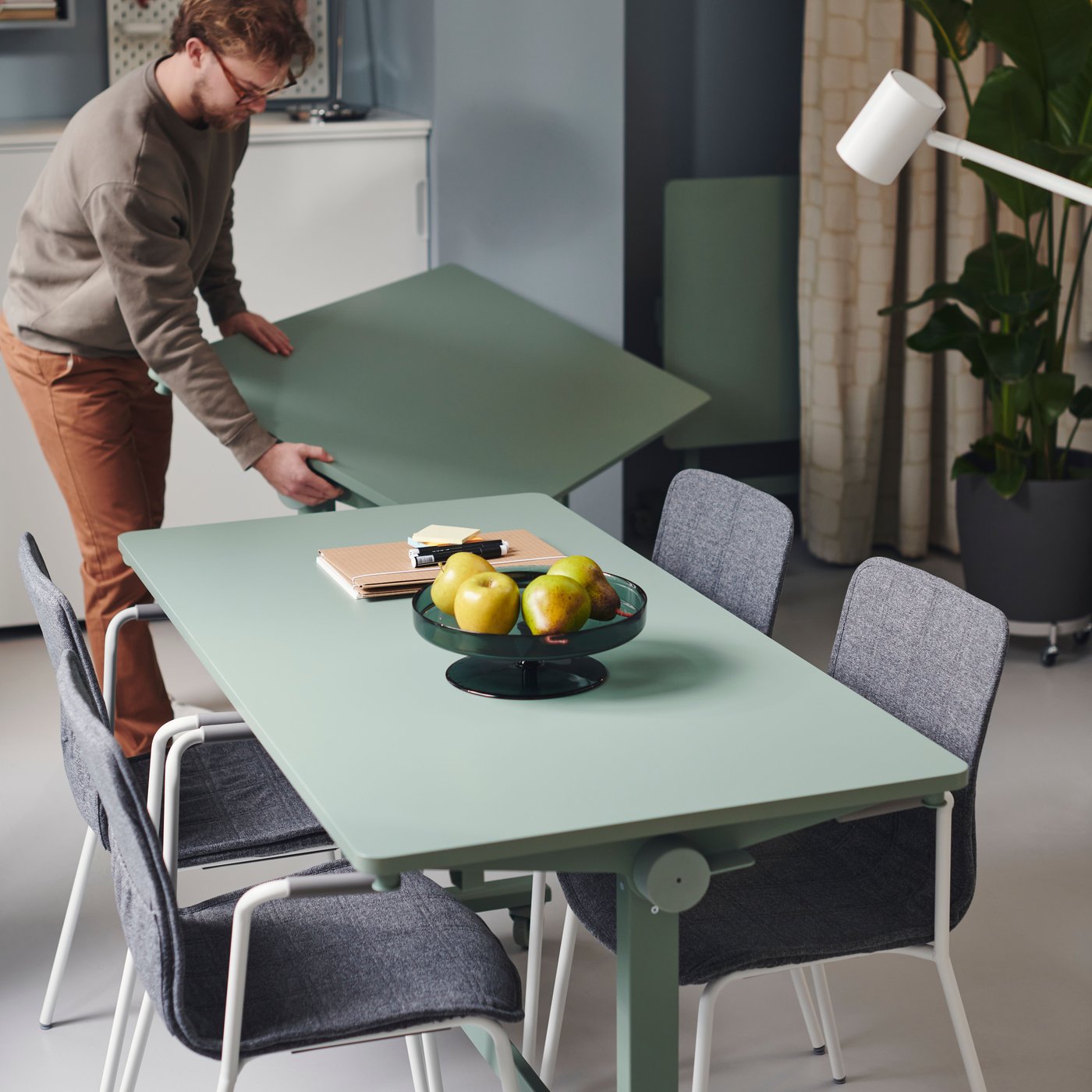 Et kontor med et MITTZON klapbord med hjul og LÄKTARE konferencestole. En person tilføjer endnu et bord.