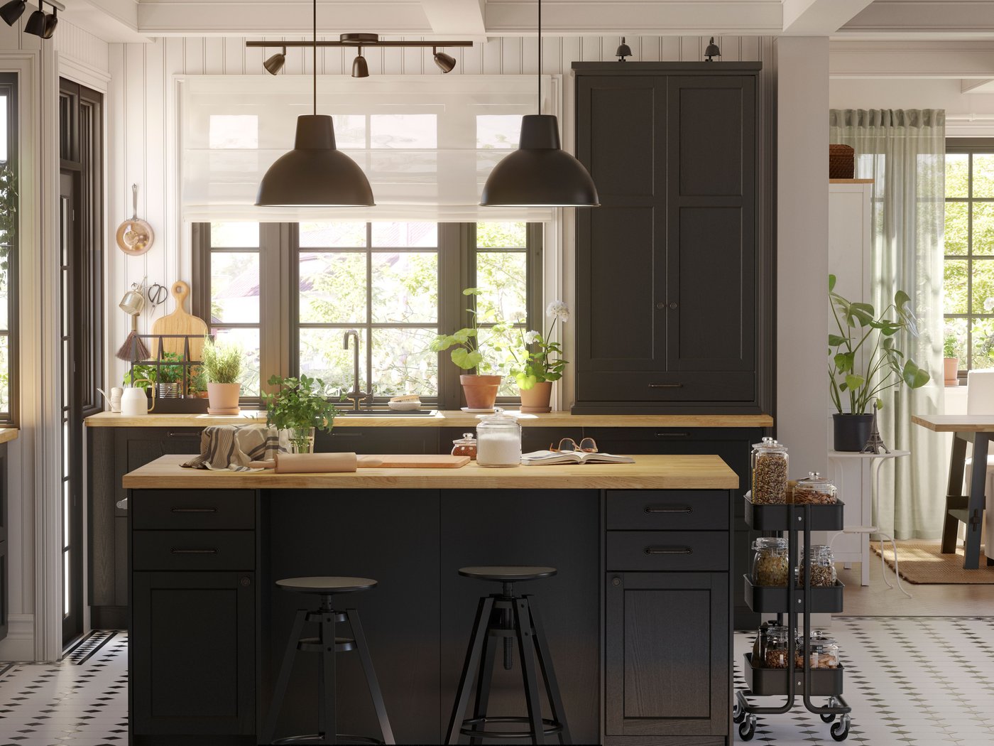 Une grande cuisine LERHYTTAN avec des façades teintées noires et un îlot de cuisine au centre avec deux suspensions noires au-dessus.