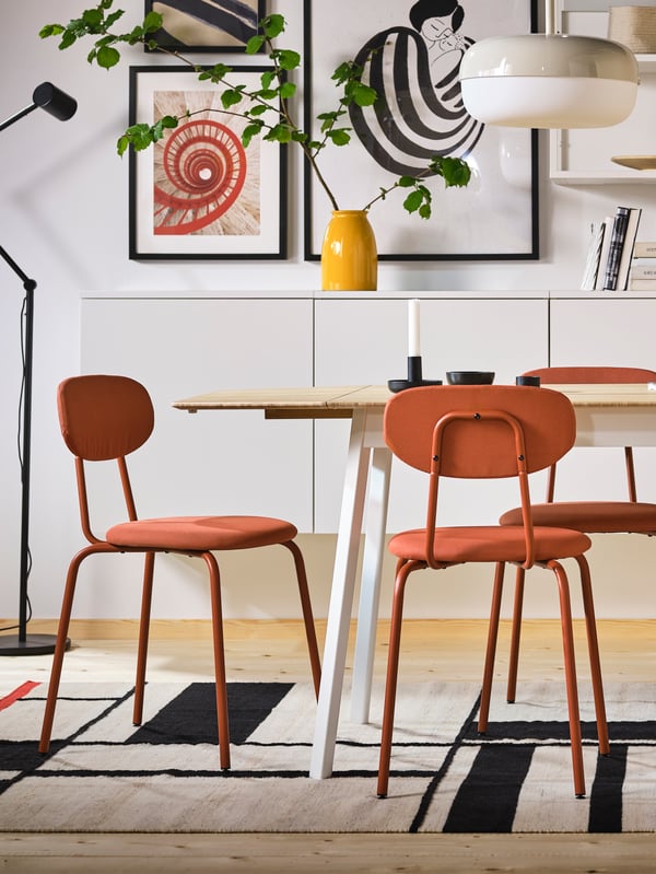 Red OSTANO chairs placed adjacent to each other in front of a dining table.