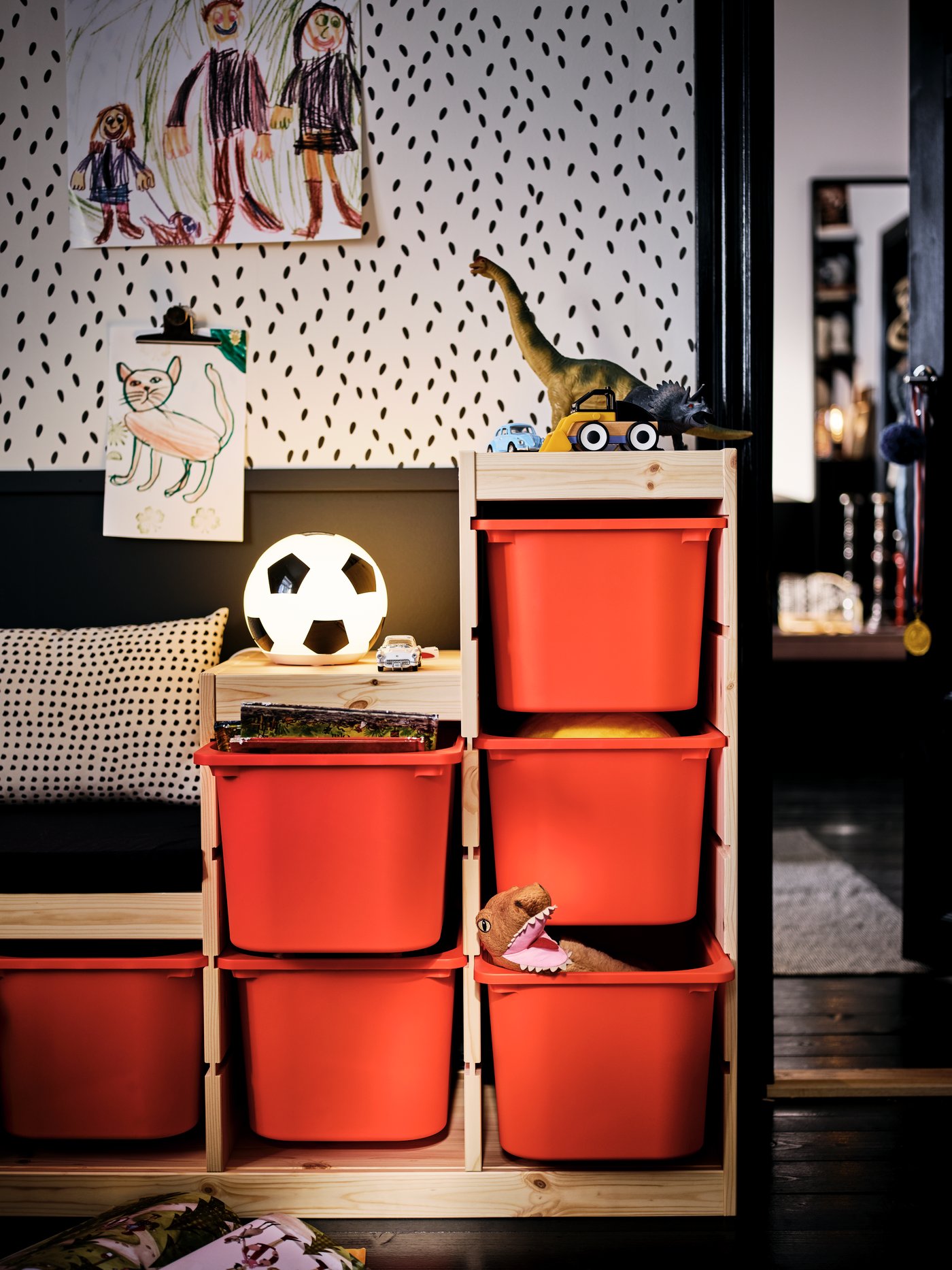 A toy-filled TROFAST unit with orange storage boxes in a kids’ room set in an otherwise black-and-white colour scheme.