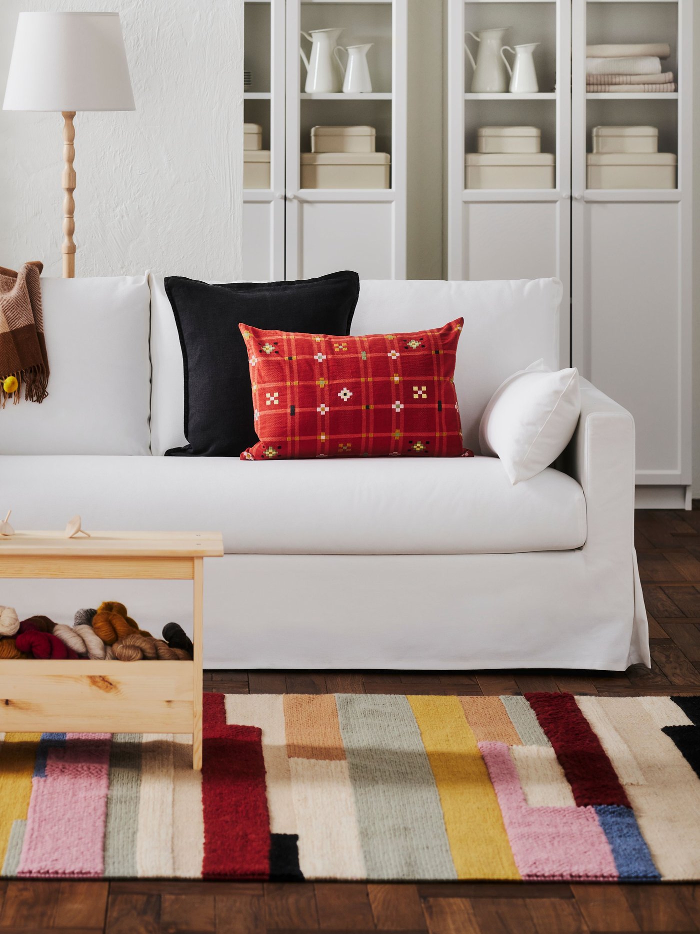 A Hallarp white HYLTARP 3 seat sofa bed in a white room on a colourful rug