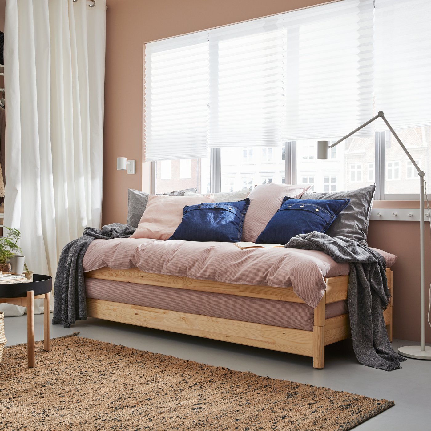 Un lit empilable UTÄKER est placé contre un mur doté d'une fenêtre, dans une chambre.