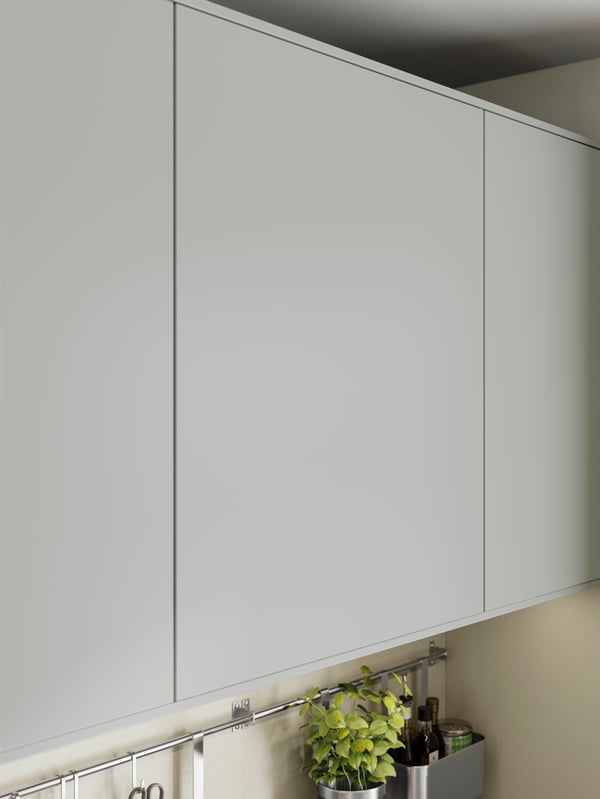 HAVSTORP light grey kitchen cabinet door with a potted plant and kitchen utensils organised on a rail underneath.