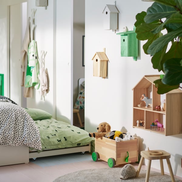 A VIHALS double bed with a trundle bed that is open by a wooden FLISAT toy storage with wheels and a FLISAT children’s stool.