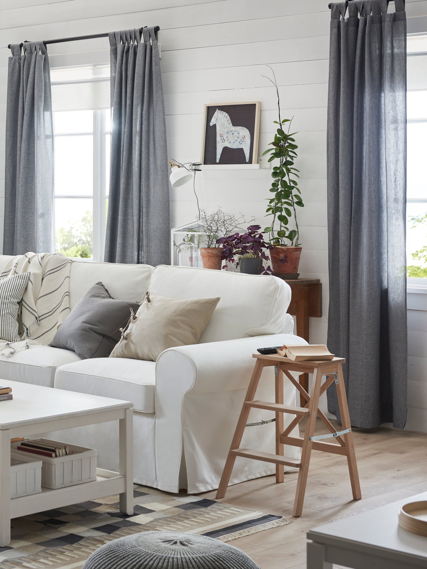 ソファとスツールがスペースを占めている明るい色調のリビングルーム。