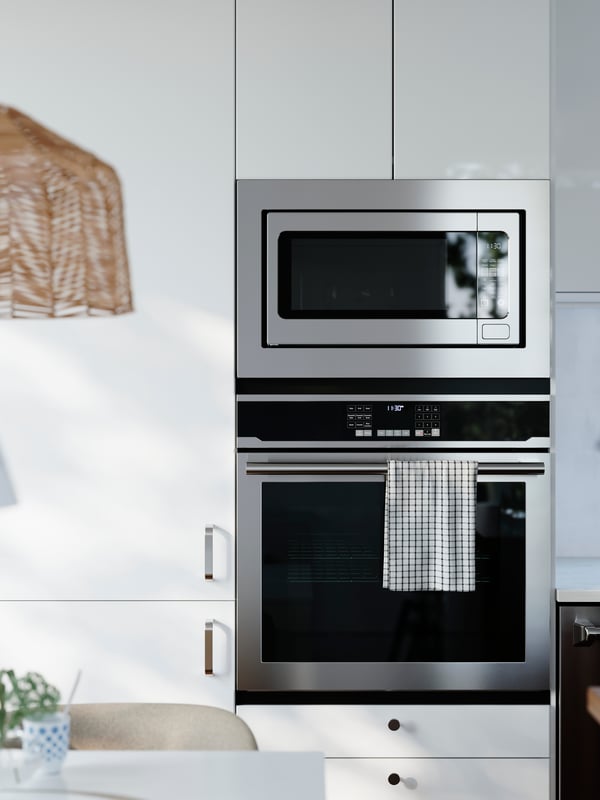 A kitchen has cabinets with glossy RINGHYLT fronts with an integrated fridge/freezer, a built-in oven and microwave oven.