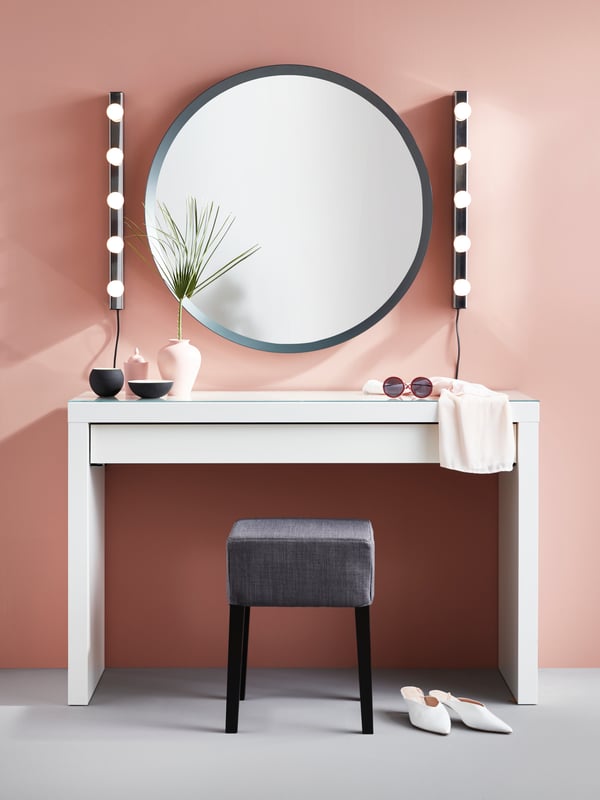 MALM toalettbord med en tund spegel och vägglampor på en rosa vägg. 