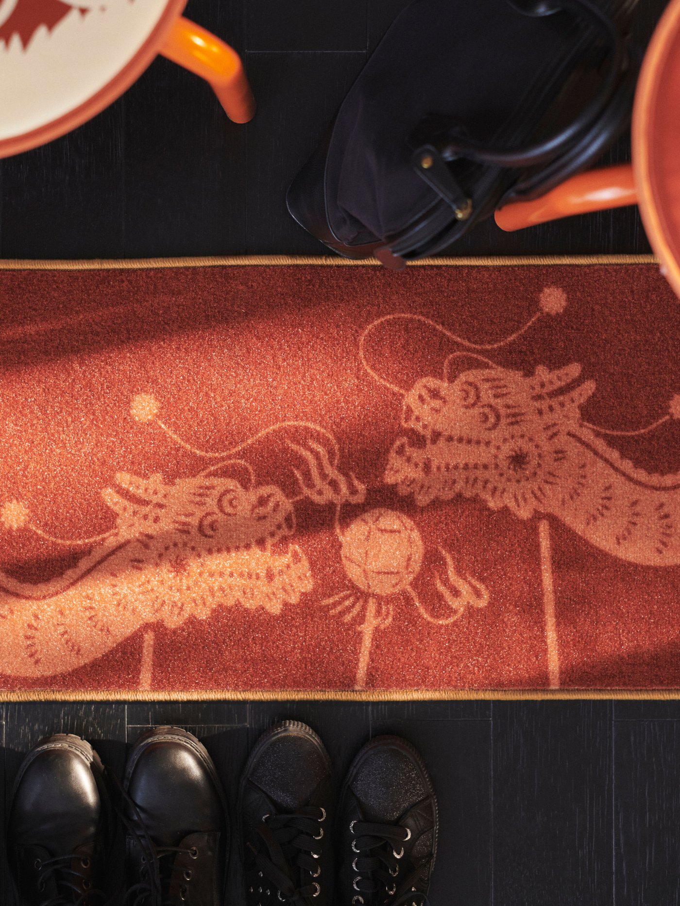 A FÖSSTA throw with a dragon motif draped over the back of a sofa, against which are two cushions in FÖSSTA cushion covers.