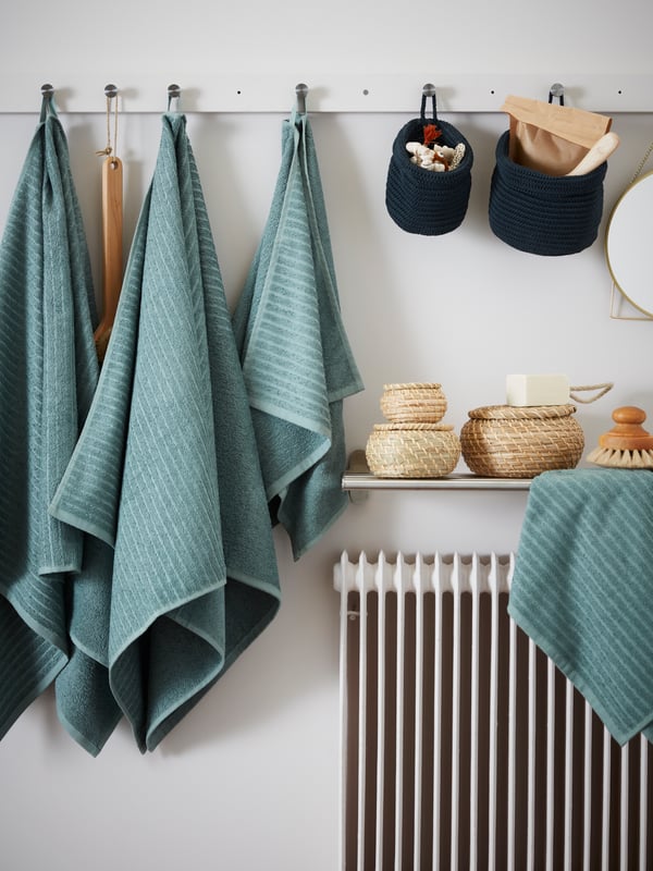  Toallas grises y accesorios de baño dispuestos sobre una superficie gris.