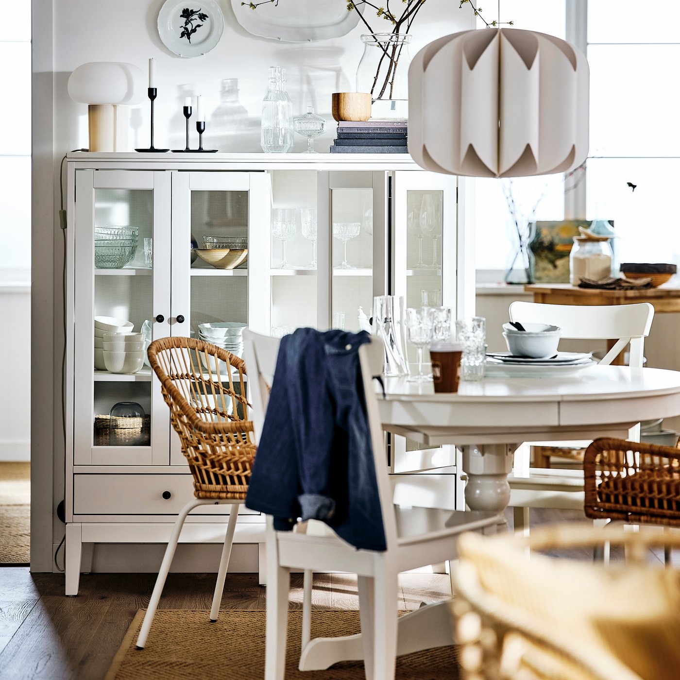 Weiss gehaltener Essbereich mit einem runden Tisch und Stühlen.