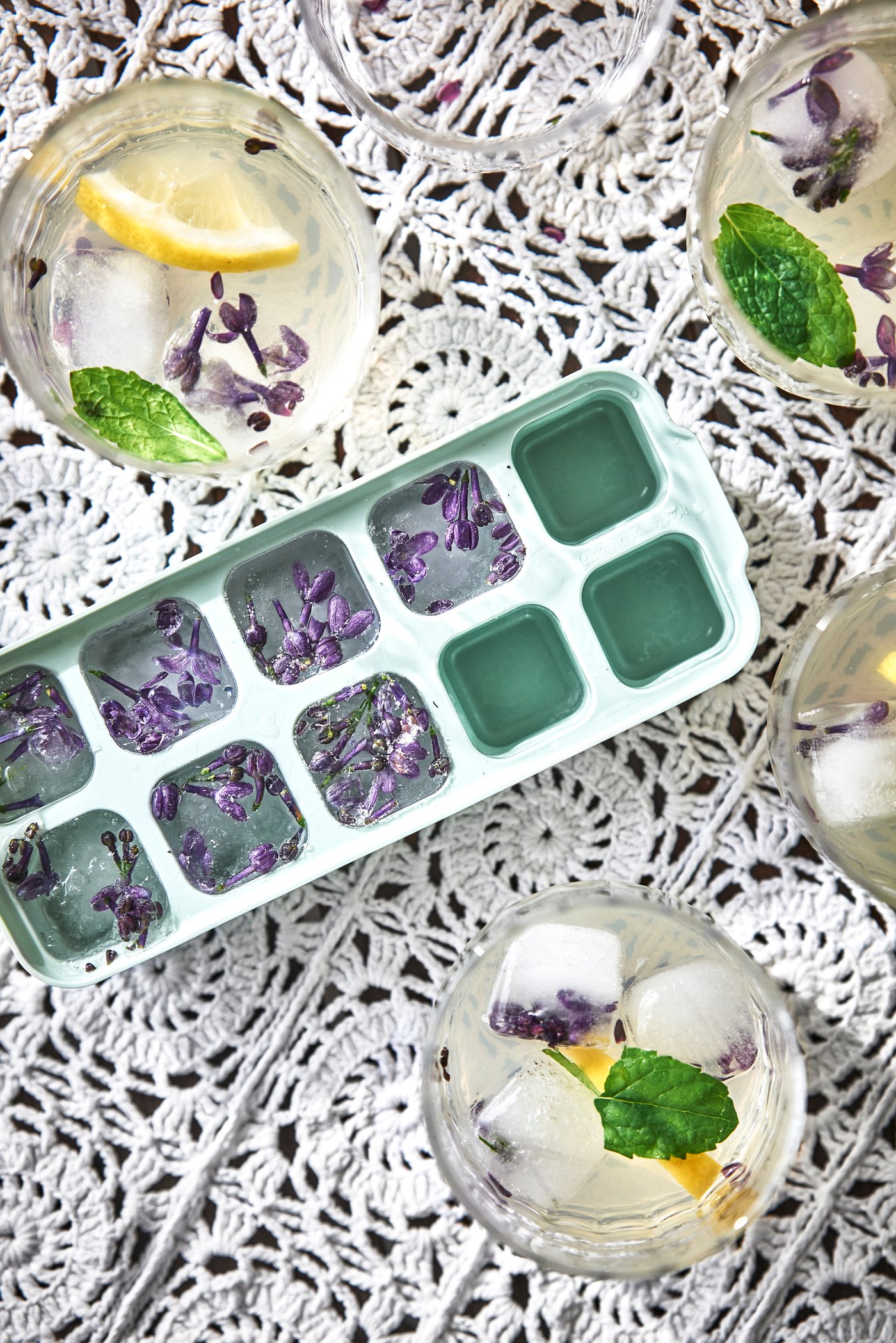 En iskubslåda syns uppifrån med två drinkar vid sidan om.