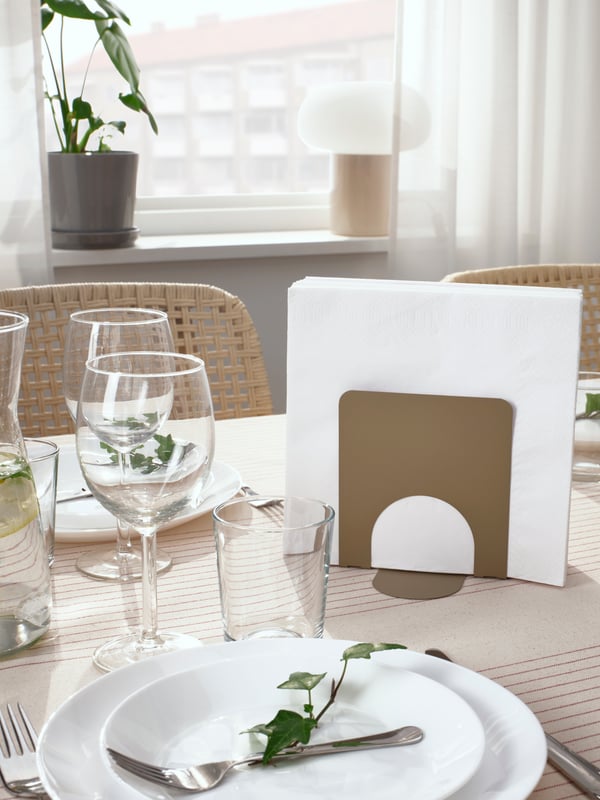 Servetthållare med vita servetter på ett dukat bord. 