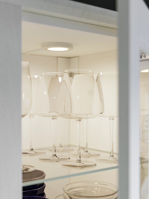 Kitchen featuring a white MITTLED LED spotlight placed above multiple white DYRGRIP red wine glasses.