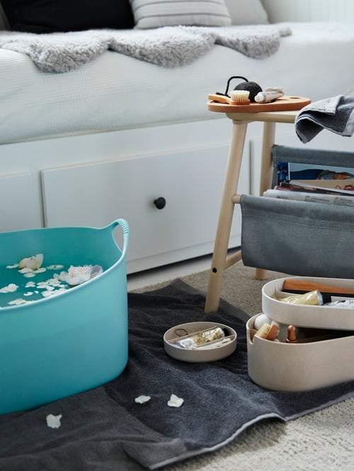 Living space has a daybed with drawers, throw, rug, towel, laundry basket, storage box with mirror lid, storage stool.