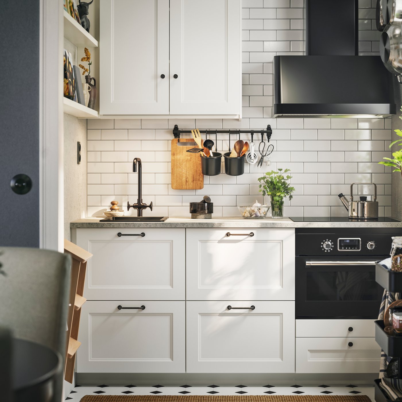 Høye skap med matt hvite AXSTAD fronter, svarte hvitevarer og hyller på en vegg i et hvitt flislagt kjøkken.