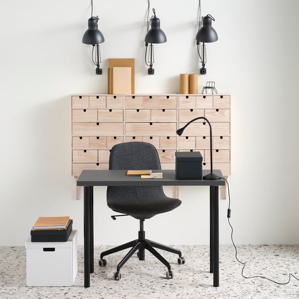 A dark grey LINNMON tabletop on black ADILS legs with a conference chair. Six MOPPE mini chests are grouped on the wall.
