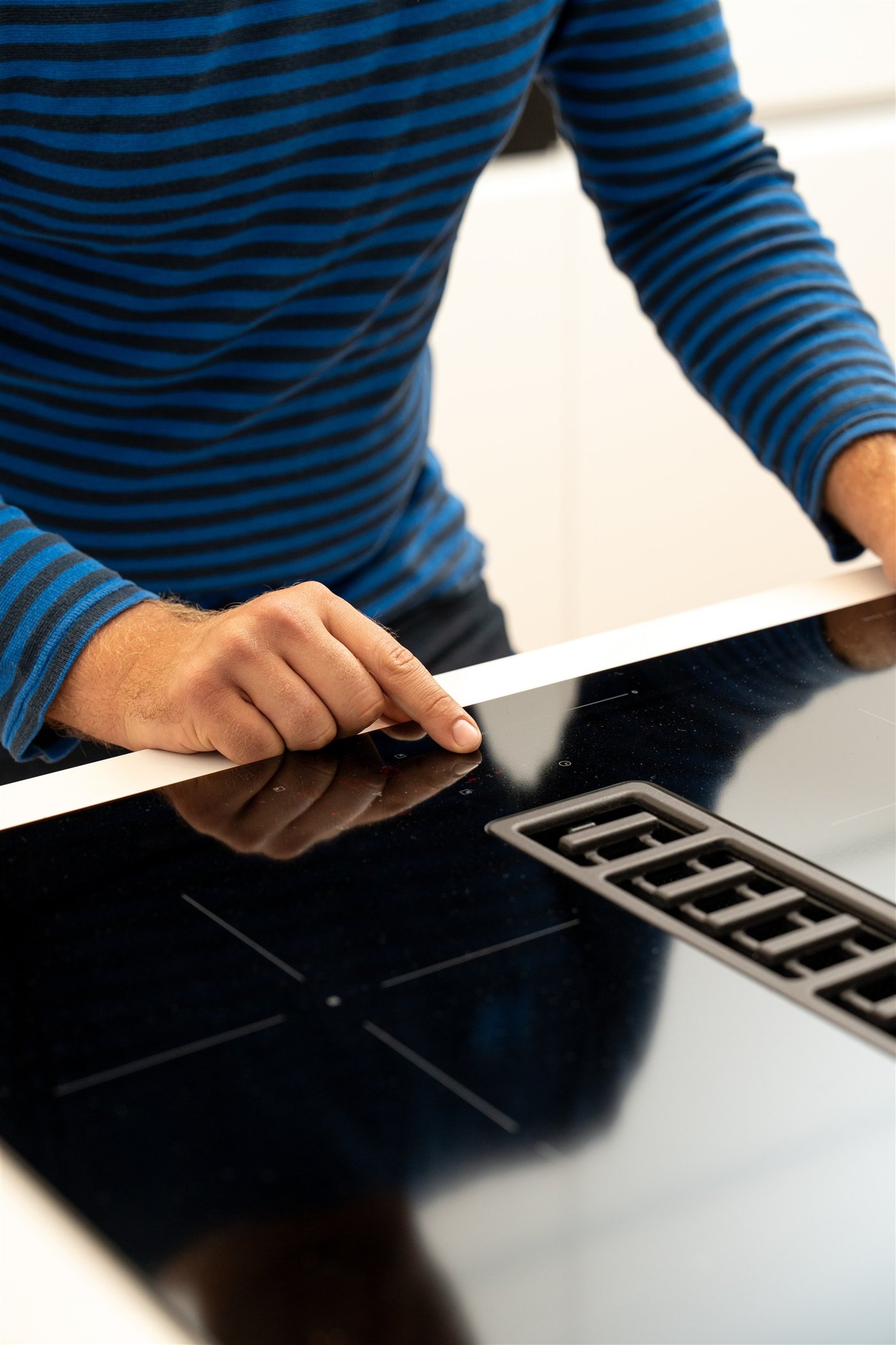 Ein IKEA Mitarbeiter testet einen Herd in einer weißen IKEA Küche