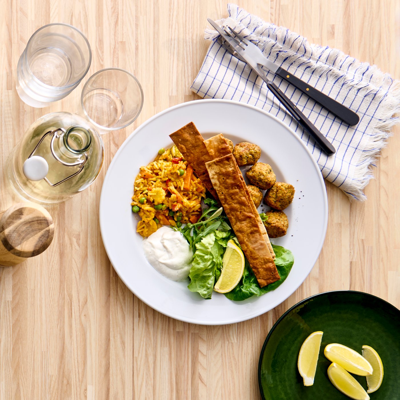 Falafel med ris og grøntsager serveret på en hvid tallerken placeret på et spisebord i birk.