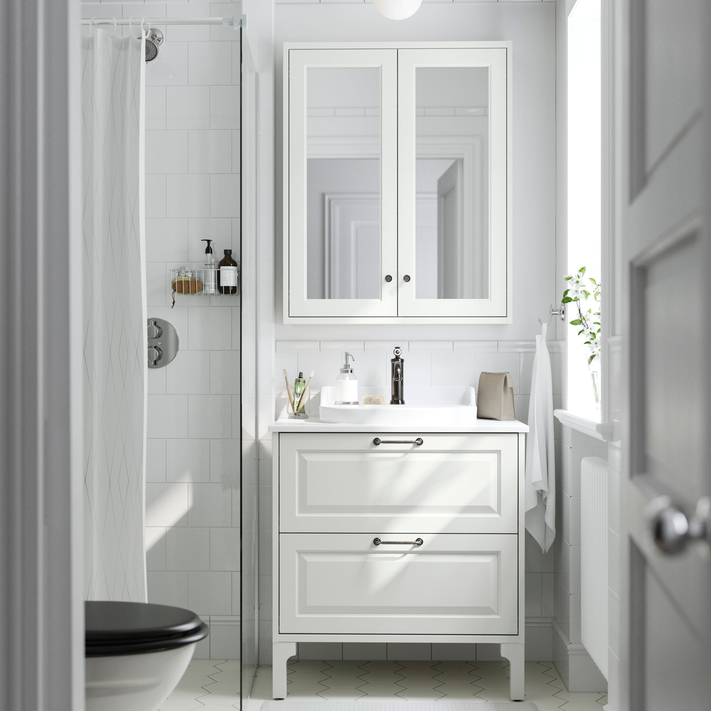 A white bathroom featuring a TÄNNFORSEN wash-stand with drawers and RUTSJÖN semi-recessed wash-basin under a mirror cabinet.