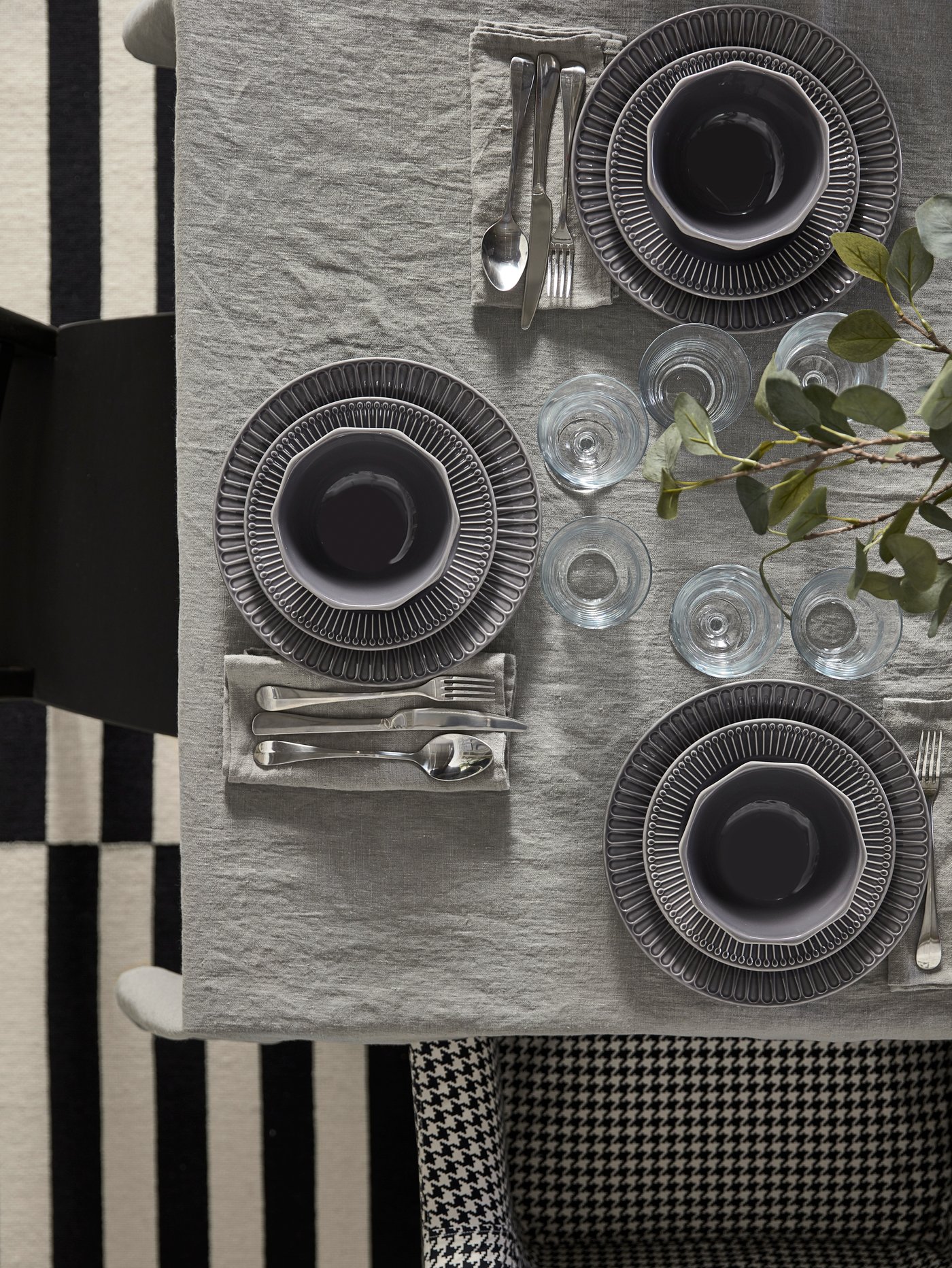 A table set with a gray tablecloth, gray linen napkins, plates and bowls in earthenware gray and cutlery in stainless steel.