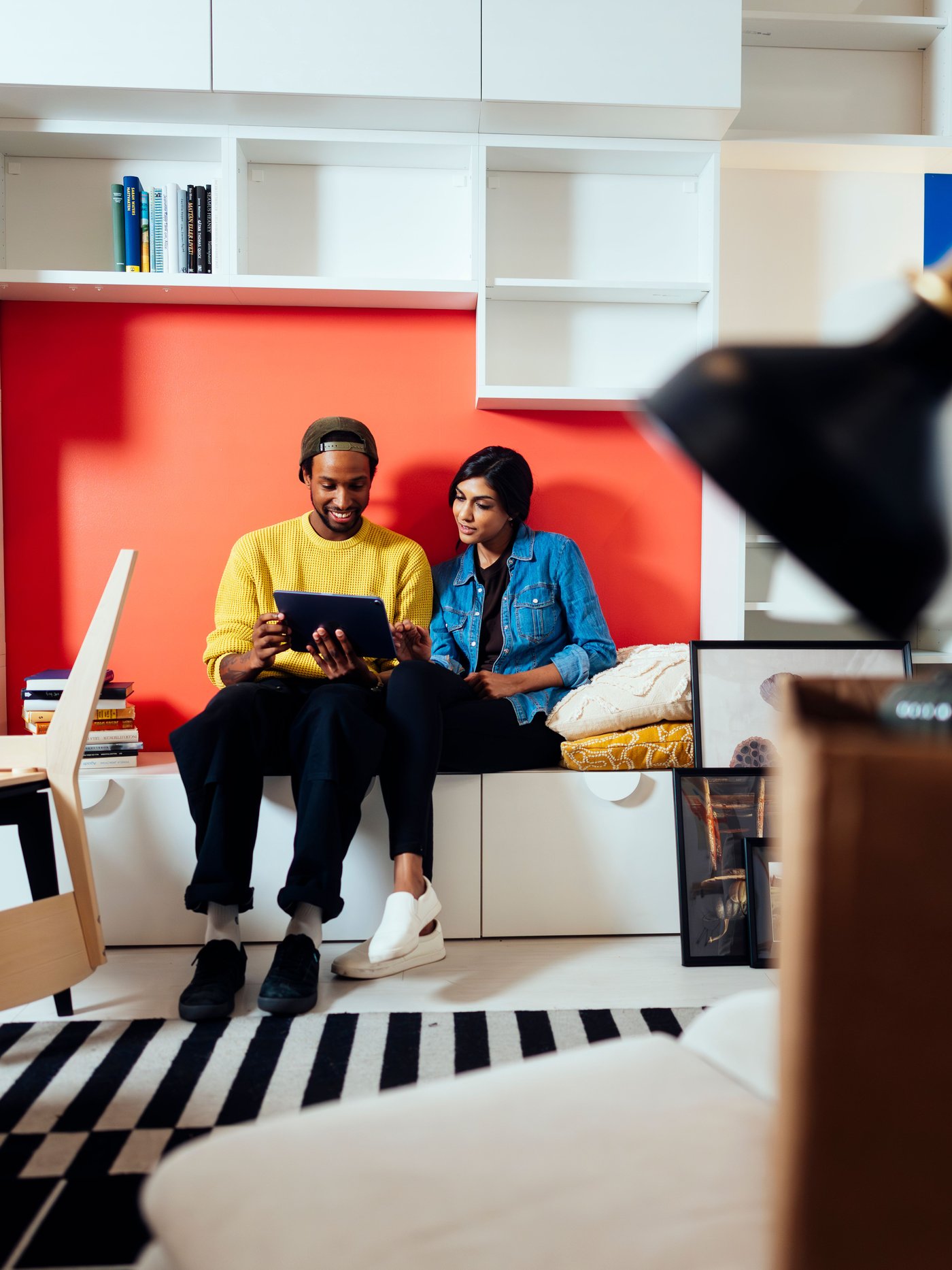 2 Personen sitzen auf einer Bank und schauen auf ein Tablet.