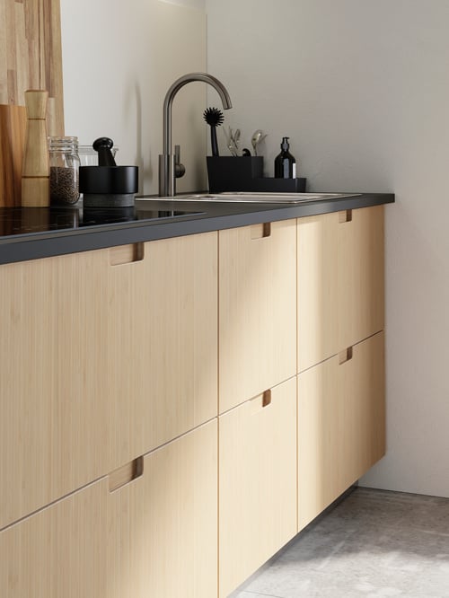 Une cuisine moderne avec des armoires à façades de tiroir beiges, un comptoir, un mitigeur et une table de cuisson à induction. 