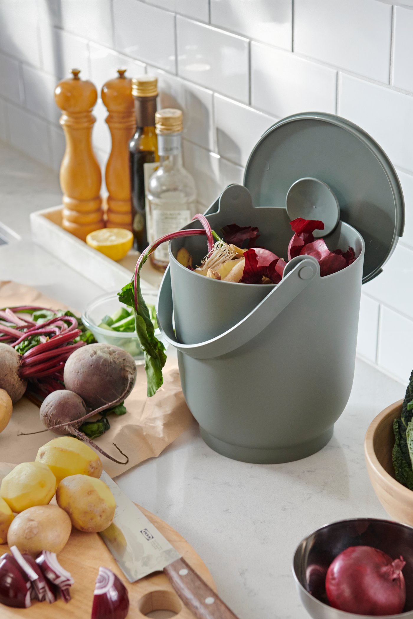 A grey-green FARMARKVAST bin with lid for organic waste in the kitchen
