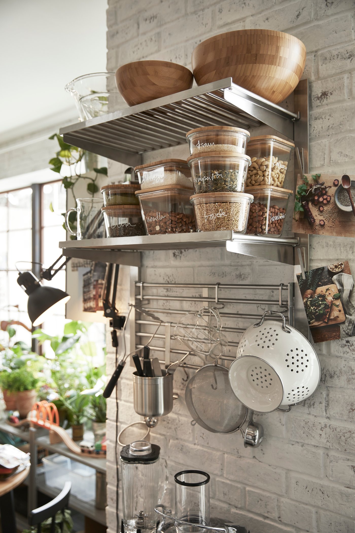 Contenants transparents remplis de grains et de légumineuses rangés sur la tablette inférieure d’un rail de suspension KUNGSFORS avec tablette et grille murale.